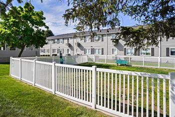 A white picket fence in front of a grey apartment building.